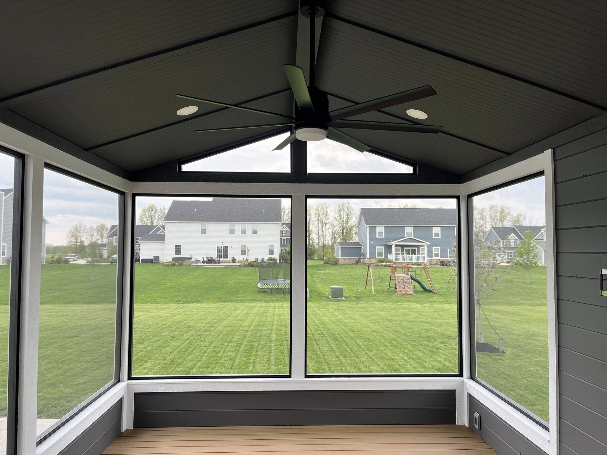 Finished screened porch interior with dark ceiling and ceiling fan